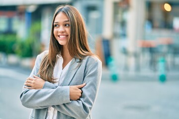 Fototapeta premium Young latin businesswoman with crossed arms smiling happy at the city.