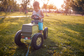 toddler enjoying ride on his plastic tractor toy