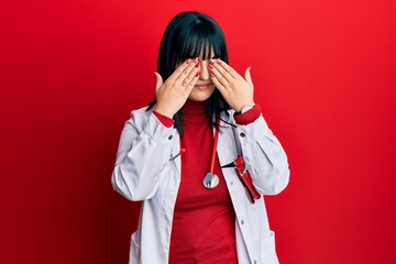 Young hispanic woman wearing doctor uniform and stethoscope rubbing eyes for fatigue and headache, sleepy and tired expression. vision problem