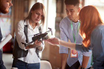 Group of young creative people in the office is learning about a drone they will use in the project