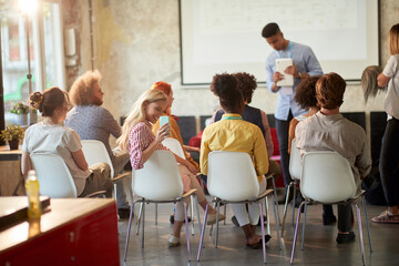 A young beautiful woman at a presentation in the office is taking a photo