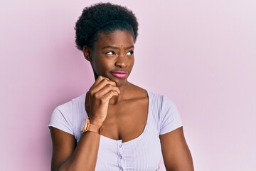 Young african american girl wearing casual clothes thinking concentrated about doubt with finger on...