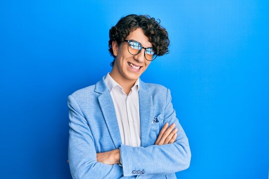 Hispanic young man wearing business jacket and glasses happy face smiling with crossed arms looking at the camera. positive person.