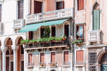 Large balcony with many flower pots on it. The facade of one of the old houses in Venice on the Grand Canal. Venice, Italy