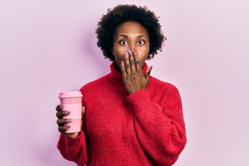Young african american woman drinking a cup of coffee covering mouth with hand, shocked and afraid...