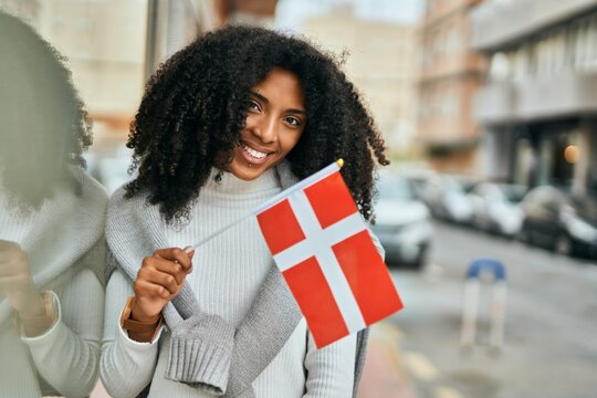 Young african american woman smiling happy holding Denmark flag at the city.