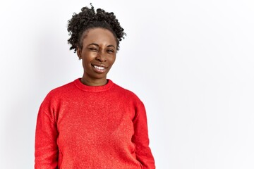 Young african american woman wearing casual clothes over isolated background winking looking at the...