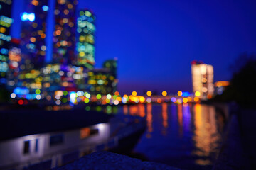 Night bokeh light in big city. Defocused illuminated skyscrappers and river of city downtown. Abstract blur defocused background.