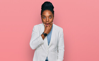 Young african american woman wearing business clothes looking fascinated with disbelief, surprise and amazed expression with hands on chin