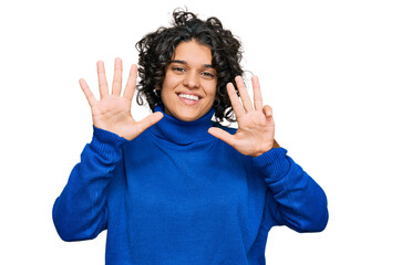 Young hispanic woman with curly hair wearing turtleneck sweater showing and pointing up with...