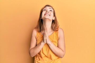 Young caucasian woman wearing casual style with sleeveless shirt begging and praying with hands...