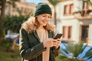 Young caucasian girl smiling happy using smartphone at the city.