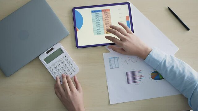 slow motion top view scene of accountant man using calculating on calculator to summarize or consider on statistic report at home office for business and financial concept