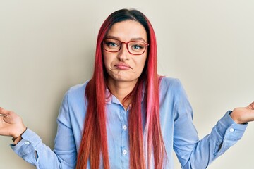 Young caucasian woman wearing casual clothes and glasses clueless and confused expression with arms...