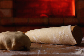 rolled dough in flour on the background of a stone oven with hot coals