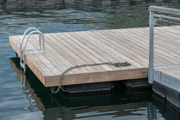 wooden pier in the lake, or floating wharf with chain and wet steps