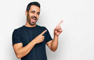 Young hispanic man wearing casual clothes smiling and looking at the camera pointing with two hands...