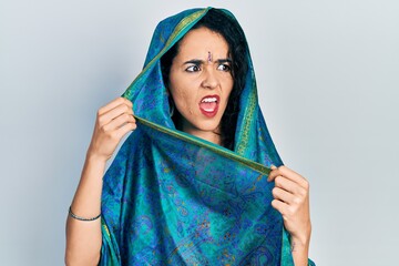 Young woman wearing bindi wearing traditional indian saree smiling with an idea or question...