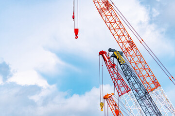 Crawler crane against blue sky and white clouds. Real estate industry. Red crawler crane use reel...