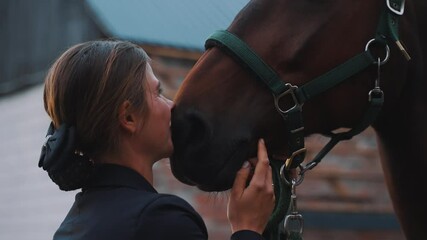 Beautiful young girl kissing her seal brown horse. Stroking and expressing her love for the horse. Bonding between horse and its owner. Love for horses. 