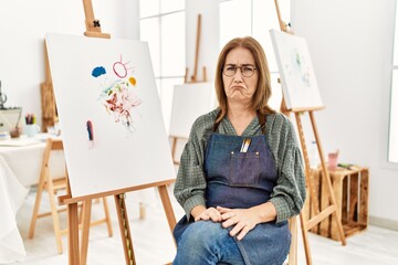 Middle age artist woman at art studio depressed and worry for distress, crying angry and afraid....