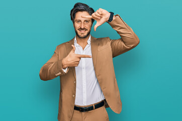 Young hispanic man wearing business clothes smiling making frame with hands and fingers with happy face. creativity and photography concept.