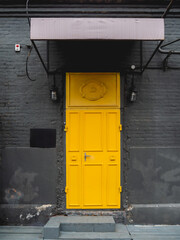 Building with black brick walls and bright yellow door. Colorful urban background.