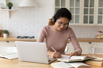 Smiling young hispanic caucasian woman in glasses wearing headphones with mic listening online...