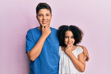 Naklejka premium Young hispanic family of brother and sister wearing casual clothes together looking confident at the camera smiling with crossed arms and hand raised on chin. thinking positive.