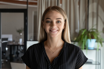 Head shot portrait close up of smiling young businesswoman intern looking at camera, standing in...