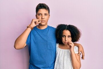 Naklejka premium Young hispanic family of brother and sister wearing casual clothes together mouth and lips shut as zip with fingers. secret and silent, taboo talking