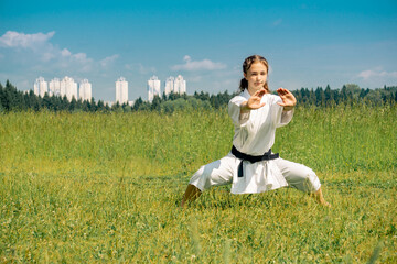 teen girl practicing karate kihon kata outdoors in kiba-dachi stance