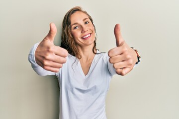 Young blonde woman wearing casual clothes approving doing positive gesture with hand, thumbs up smiling and happy for success. winner gesture.