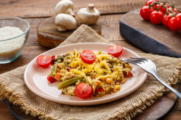 Risotto with beefs and cheese in a plate on a wooden background on a napkin next to rice mushrooms and tomatoes on planks.
