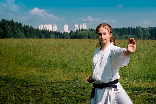 teen girl training karate kata outdoors, performing a strike oi zuki