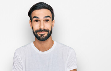 Young hispanic man wearing casual white t shirt puffing cheeks with funny face. mouth inflated with air, crazy expression.