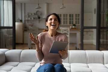Sincere happy young hispanic woman celebrating internet success or giveaway lottery win, holding...