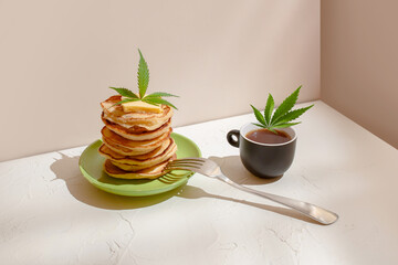 Healthy breakfast with cannabis. Tea, fresh pancakes and hemp leaf on the table
