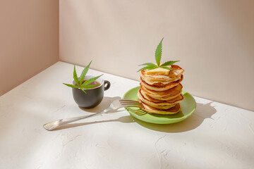 Healthy breakfast with cannabis. Tea, fresh pancakes and hemp leaf on the table