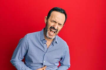 Fototapeta premium Middle age hispanic man wearing casual clothes with hand on stomach because nausea, painful disease feeling unwell. ache concept.