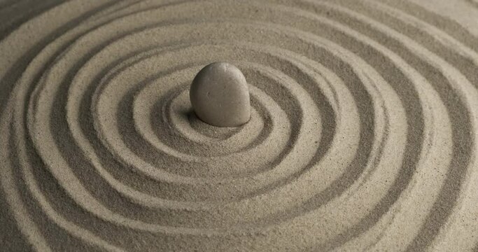 Rotation of the white stone in the center of the sand spiral. Close-up of patterns in the sand. Sand texture