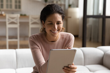 Happy attractive hispanic woman using digital computer tablet, web surfing information, shopping in...