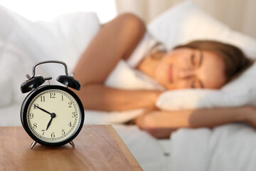 Beautiful young woman sleeping and smiling while lying in bed comfortably and blissfully on the...