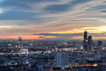 Bangkok, thailand - Jul  02, 2021 : Aerial view of Bangkok city Overlooking Skyscrapers and the Bridge crosses the Chao Phraya river with bright glowing lights at dusk. Selective focus.