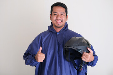 Adult Asian man wearing rain coat and bring motorcycle helmet