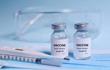 Two Bottle of Covid-19 vaccine to immunize from the Delta Variant Coronavirus, syringe , face mask,body thermometer and protective glasses on blue background.The concept of medicine, healthcare