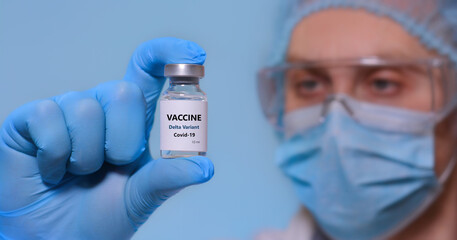 Fototapeta premium A doctor in medical gloves and a protective mask holds a bottle with coronavirus Covid19 Delta variant strain vaccine.The concept of medicine, healthcare and science.Coronavirus vaccine