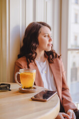 Obraz na płótnie Canvas mug with orange tea on the cafe table woman on background