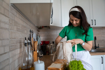 woman disassembles purchases at home kitchen
