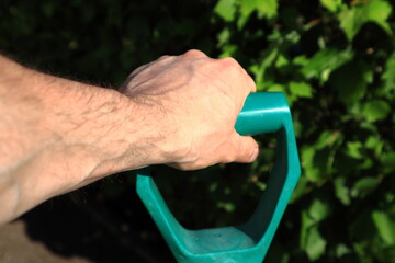 A mans hand holding a firm grip on the top of a digging shovel. Close up and isolated. Sunny day. Conecpt of hobby and work mixed together. Stockholm, Sweden, Europe.